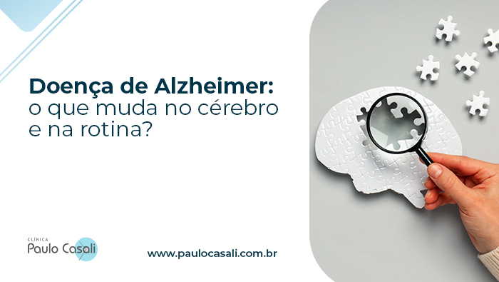 Doença de Alzheimer: o que muda no cérebro e na rotina? 1 Mão segurando lupa sobre peça faltante em quebra-cabeça em formato de cérebro, simbolizando investigação de alterações cognitivas.