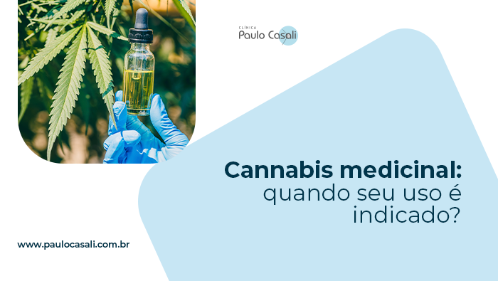 Cannabis medicinal: quando seu uso é indicado? 1 Frasco com óleo de cannabis medicinal sendo segurado por mão com luva, diante de folhas da planta em ambiente de cultivo.